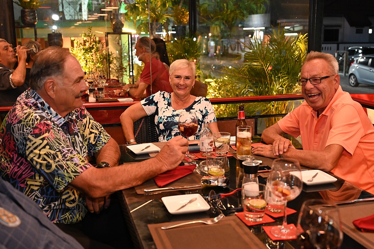Three friends toasting over dinner at a restaurant.